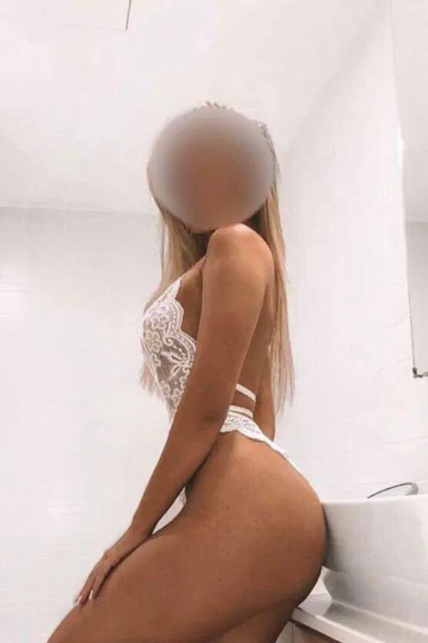 Birmingham escort Lucy poses in a white room wearing a lacy white outfit