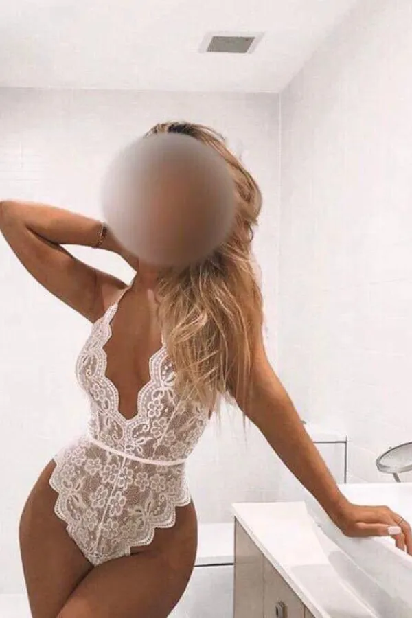 Sexy escort Lucy poses in a white kitchen wearing a lacy white outfit